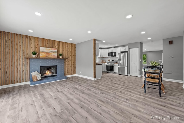 1140 Division St, Geneva, IL 60134 - living room with recessed lighting, baseboards, a brick fireplace, wooden walls, and light wood finished floors