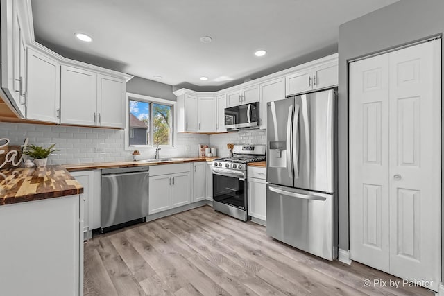 1140 Division St, Geneva, IL 60134 - kitchen featuring appliances with stainless steel finishes, butcher block counters, a sink, light wood-style flooring, and white cabinetry