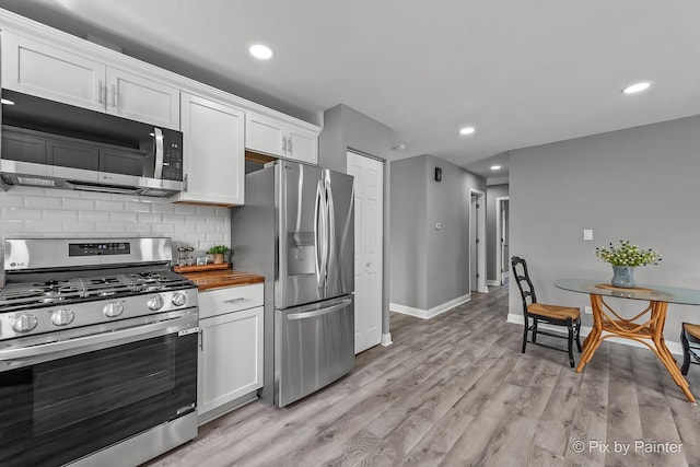 1140 Division St, Geneva, IL 60134 - kitchen with stainless steel appliances, wood counters, white cabinetry, decorative backsplash, and light wood-style flooring