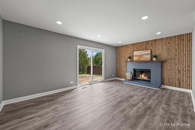 1140 Division St, Geneva, IL 60134 - unfurnished living room featuring a fireplace, wooden walls, recessed lighting, wood finished floors, and baseboards