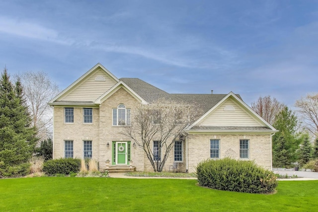 view of front facade with a front yard and a shingled roof