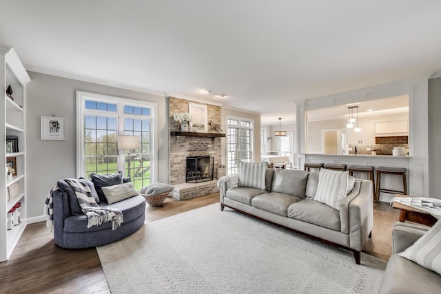 living area featuring wood finished floors, a fireplace, crown molding, and baseboards