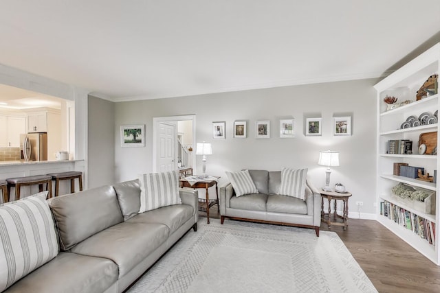 living area featuring wood finished floors, baseboards, and crown molding
