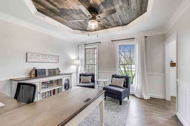 living area with a tray ceiling, a ceiling fan, wood ceiling, ornamental molding, and wood finished floors