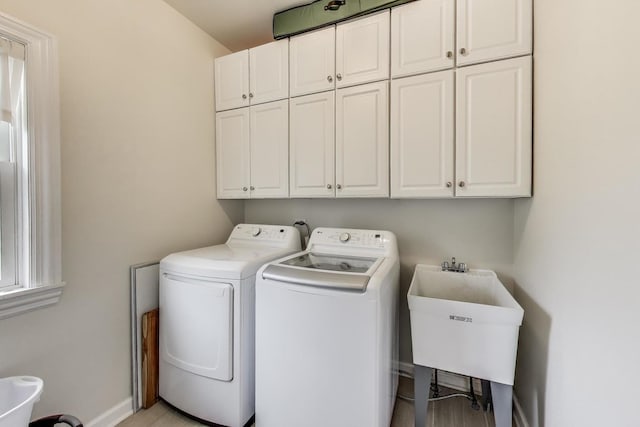 laundry room featuring cabinet space, washing machine and dryer, baseboards, and light wood-type flooring