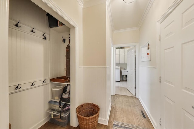 mudroom featuring wainscoting, wood finished floors, ornamental molding, and a sink
