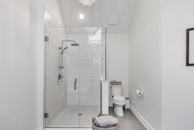 bathroom featuring toilet, a shower stall, and baseboards