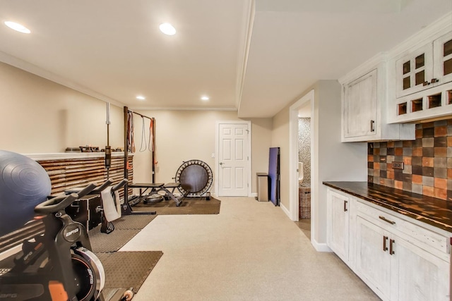 exercise area featuring recessed lighting, light colored carpet, baseboards, and ornamental molding