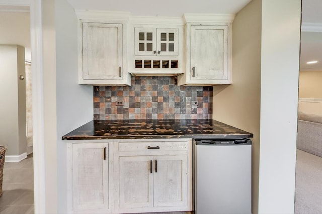 kitchen featuring dark countertops, refrigerator, tasteful backsplash, tile patterned flooring, and glass insert cabinets