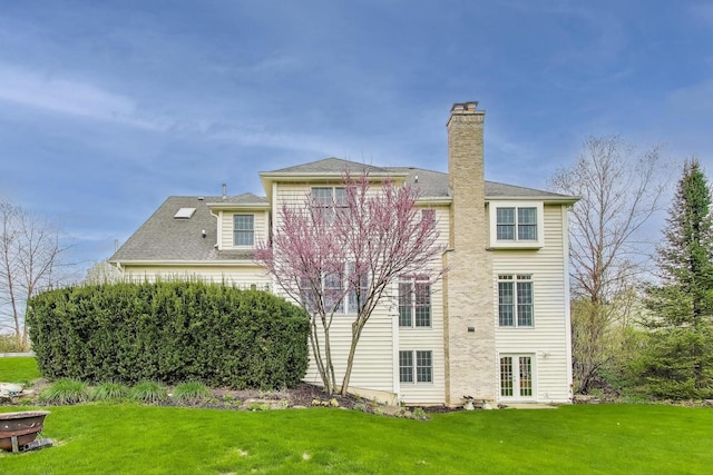 back of house featuring a lawn, french doors, and a chimney