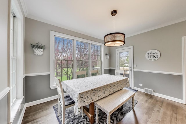 dining space featuring ornamental molding, wood finished floors, and baseboards