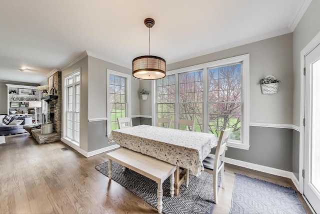 dining area with crown molding, wood finished floors, baseboards, and a large fireplace