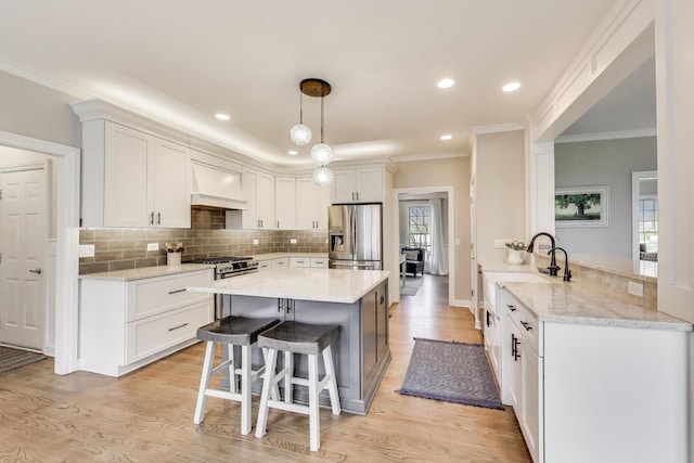 kitchen with appliances with stainless steel finishes, light wood finished floors, a kitchen breakfast bar, custom exhaust hood, and backsplash