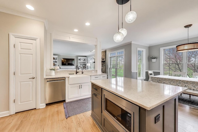 kitchen featuring a sink, appliances with stainless steel finishes, ornamental molding, white cabinets, and light wood-type flooring