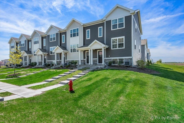 multi unit property with a front yard, stone siding, and a residential view