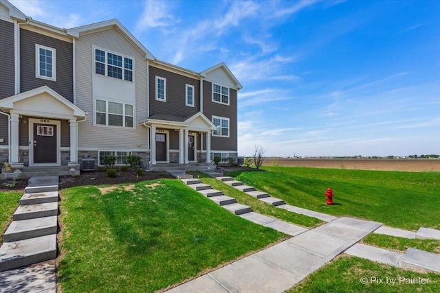 view of front of house with central AC unit, a front lawn, and stone siding
