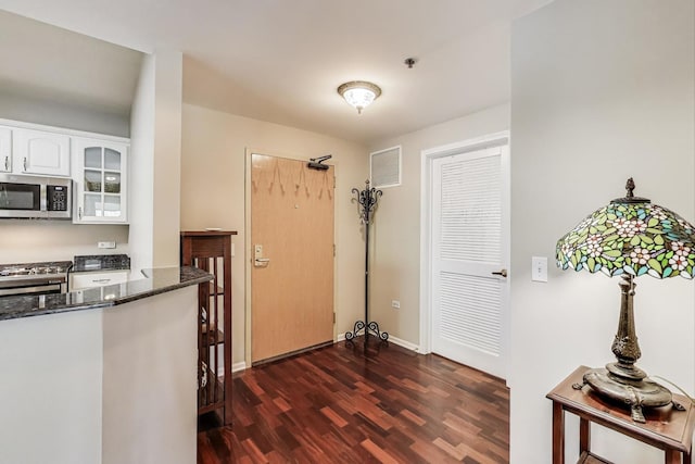 440 W Mahogany Ct Unit 209, Palatine, IL 60067 - kitchen featuring appliances with stainless steel finishes, dark wood-style flooring, dark stone countertops, and white cabinets