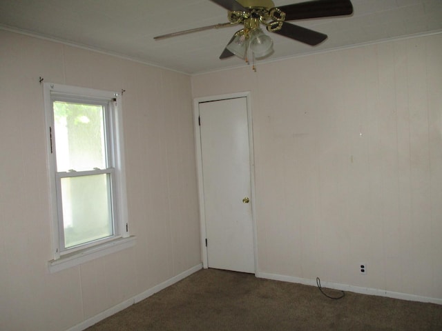 carpeted empty room featuring ornamental molding, a ceiling fan, and baseboards