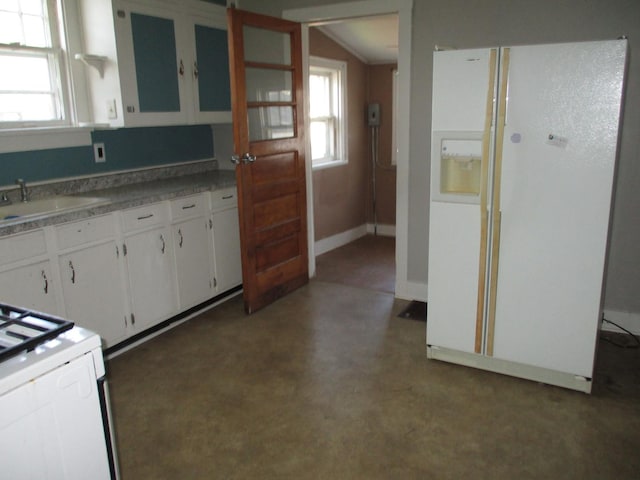kitchen with white appliances, white cabinets, a sink, plenty of natural light, and vaulted ceiling