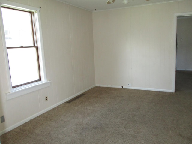 empty room with carpet flooring, a ceiling fan, baseboards, and crown molding