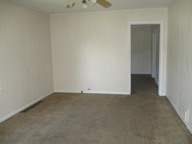 empty room with carpet flooring, crown molding, a ceiling fan, and baseboards