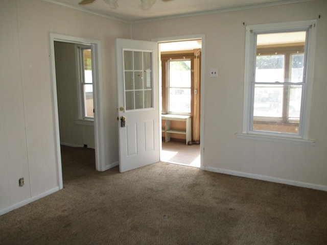 carpeted empty room with crown molding, healthy amount of natural light, and baseboards