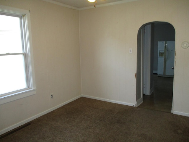 carpeted empty room with arched walkways, baseboards, and ceiling fan