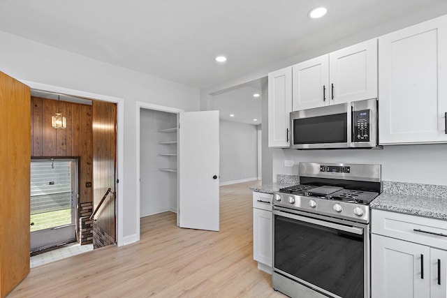 kitchen with stainless steel appliances, light wood finished floors, light stone counters, white cabinetry, and recessed lighting