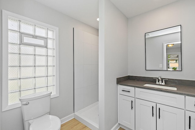 full bath with toilet, tiled shower, vanity, baseboards, and wood finished floors