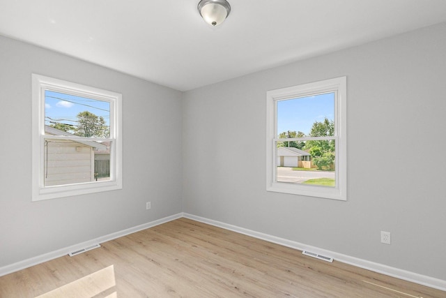 unfurnished room featuring plenty of natural light, light wood-style floors, and baseboards