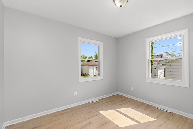 empty room featuring plenty of natural light, baseboards, and light wood-style flooring