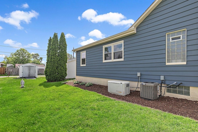 view of home's exterior with central AC, a shed, a lawn, and an outbuilding