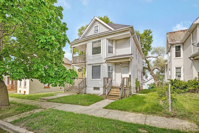 view of front of property featuring a balcony and a front yard