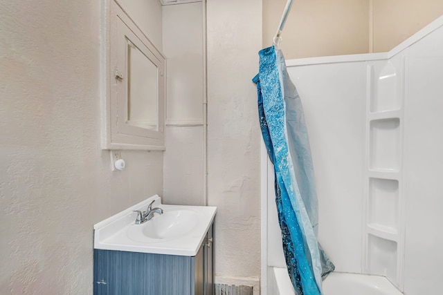 bathroom featuring a textured wall, vanity, and shower / bath combo