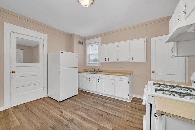 kitchen featuring white appliances, light countertops, under cabinet range hood, and a sink