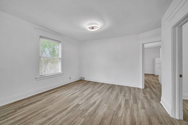 unfurnished bedroom with light wood finished floors, baseboards, and washer / dryer