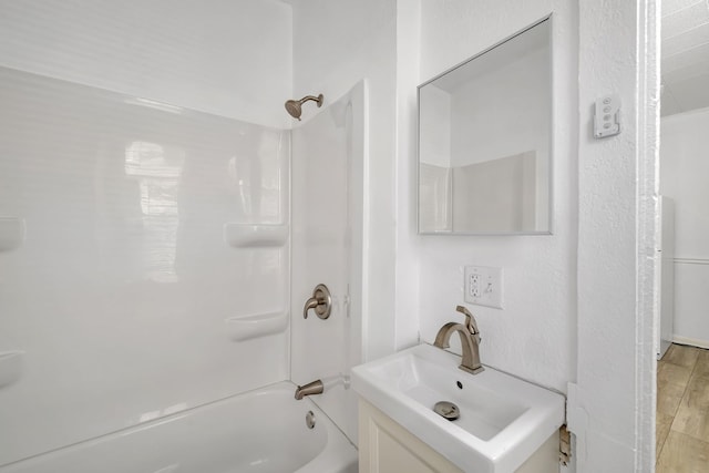 bathroom featuring washtub / shower combination, vanity, and wood finished floors