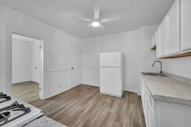 kitchen featuring white appliances, a sink, light wood-style floors, white cabinetry, and light countertops