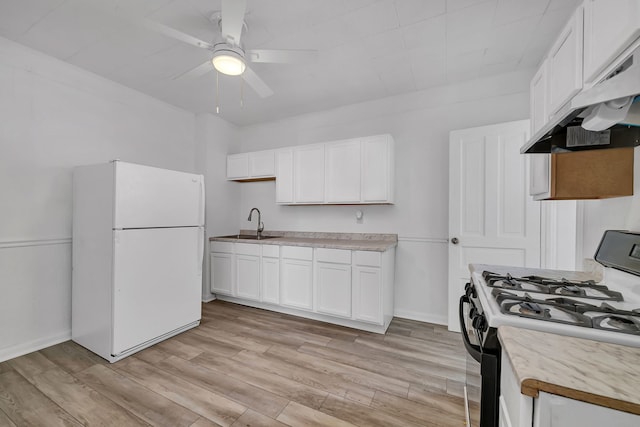 kitchen featuring gas range, freestanding refrigerator, white cabinets, a ceiling fan, and under cabinet range hood