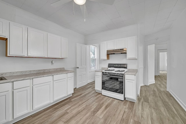 kitchen featuring white gas range oven, under cabinet range hood, ceiling fan, light wood finished floors, and white cabinetry