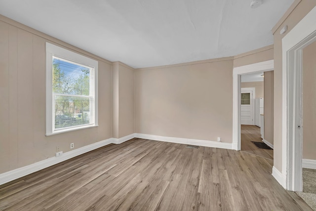 empty room with light wood-style flooring, baseboards, and a smoke detector