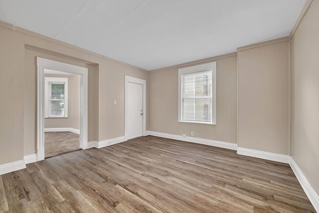 spare room with healthy amount of natural light, wood finished floors, and baseboards