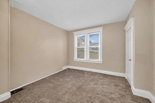 empty room with dark carpet and baseboards