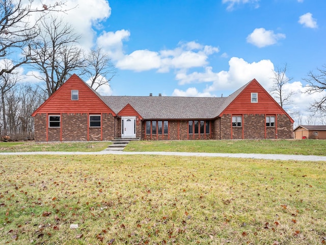view of front of property with a front lawn, roof with shingles, and brick siding