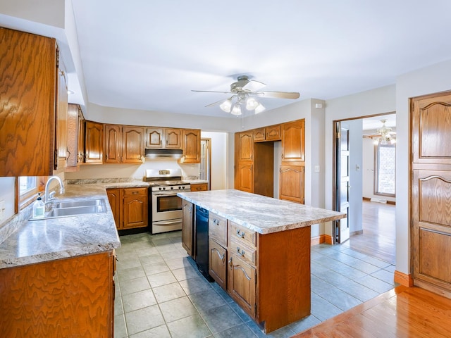 kitchen with gas range, a sink, ceiling fan, under cabinet range hood, and a center island