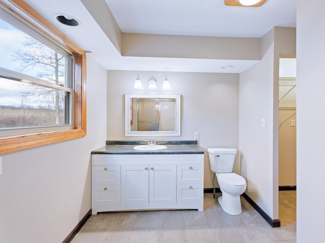 bathroom featuring baseboards, toilet, and vanity
