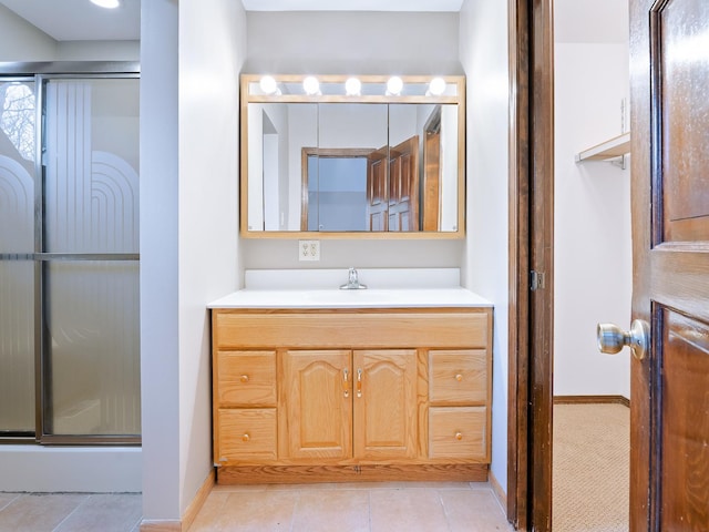 bathroom featuring baseboards, a shower with shower door, tile patterned flooring, and vanity