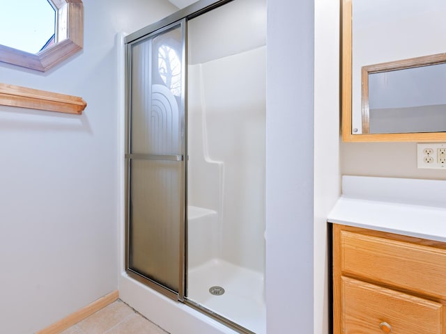bathroom with a stall shower, tile patterned flooring, a skylight, and vanity