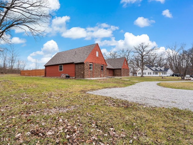 view of property exterior with a shingled roof, a yard, and brick siding
