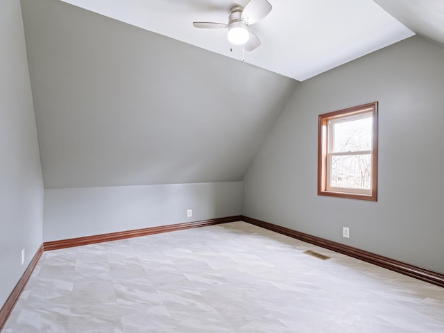 additional living space with vaulted ceiling, a ceiling fan, and baseboards